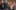 The company of By Royal Appointment with their arms around each other and smiling at the camera.
