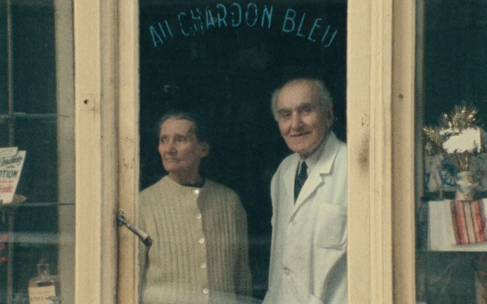 Two older people stood in a window.