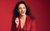 Janine Harouni Janine Harouni in a red cord suit laughing against a red background.