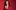 Janine Harouni in a red cord suit laughing against a red background.