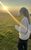Lauren Felsenstein Lauren Felsenstein looking away from the camera in a field of grass as the sun sets in the background.