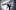 Old photo of Paul Young standing on his left leg with his left knee up by his chest. He has a dark 70s-style haircut, wearing a long coat, white shirt and black trousers.