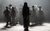 Fiddler on the Roof Ensemble walking forward on a dark stage as a silhouetted figure looks back at them