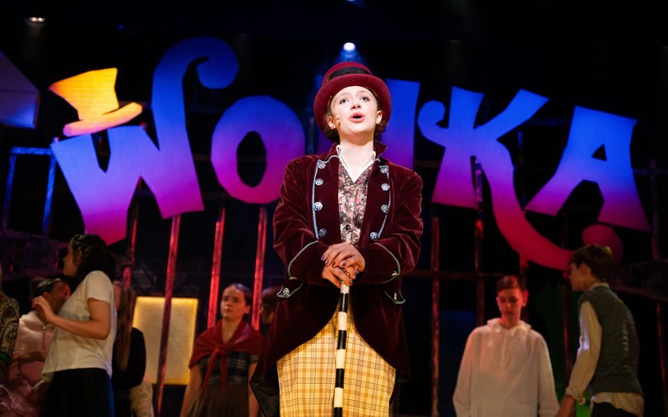 Willy Wonka stood with his factory gates and cane