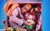 Out of the Box Man cramped inside of a pink box alongside various toys and other objects like an exercise ball. He is holding a toy stuffed dog.