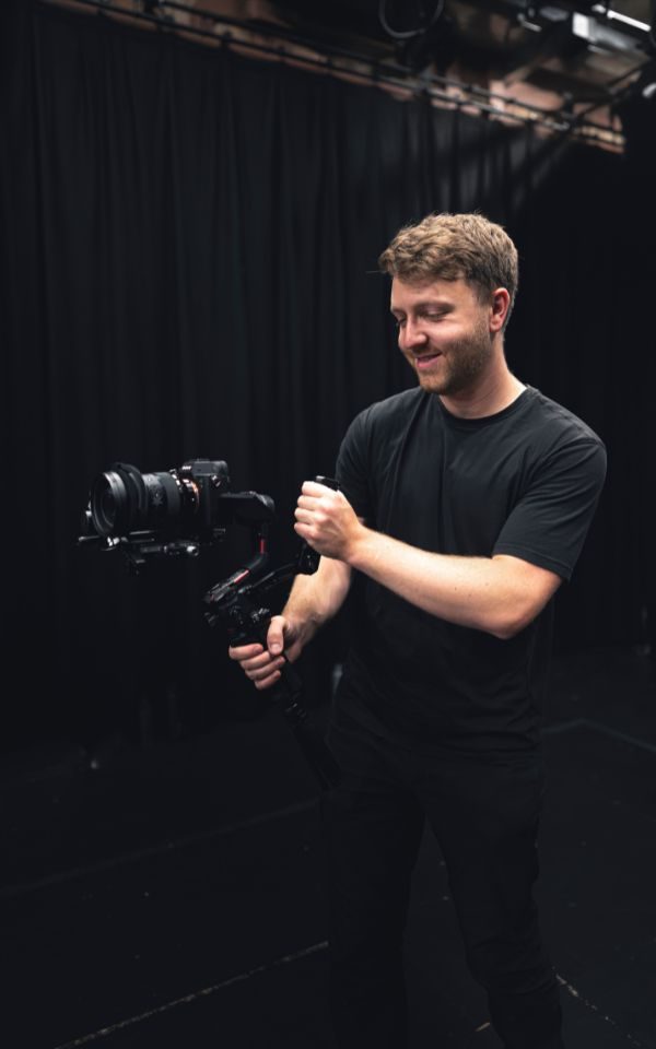 Chris Coote in an all black studio setting operates a large digital camera.