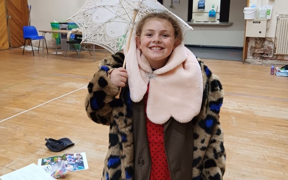A girl at the LHT Unwrapped Drama Day dresses up as the Queen of Hearts with a leopard print coat, pink shawl, red dress and umbrella