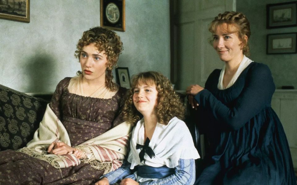 Three women of different generations, all with blonde ringlets and eighteenth century period costumes.