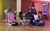 LHT Unwrapped Drama Day 2025 Four teenagers with hats and props perform a short piece in the Grand Studio with yellow and pink lighting