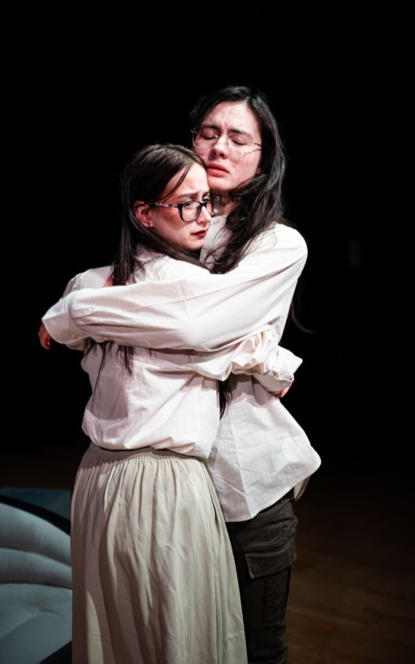 The Maladies Production at Seven Arts Two actors hold each other, one with their eyes shut, the other looking off thoughtfully into the distance