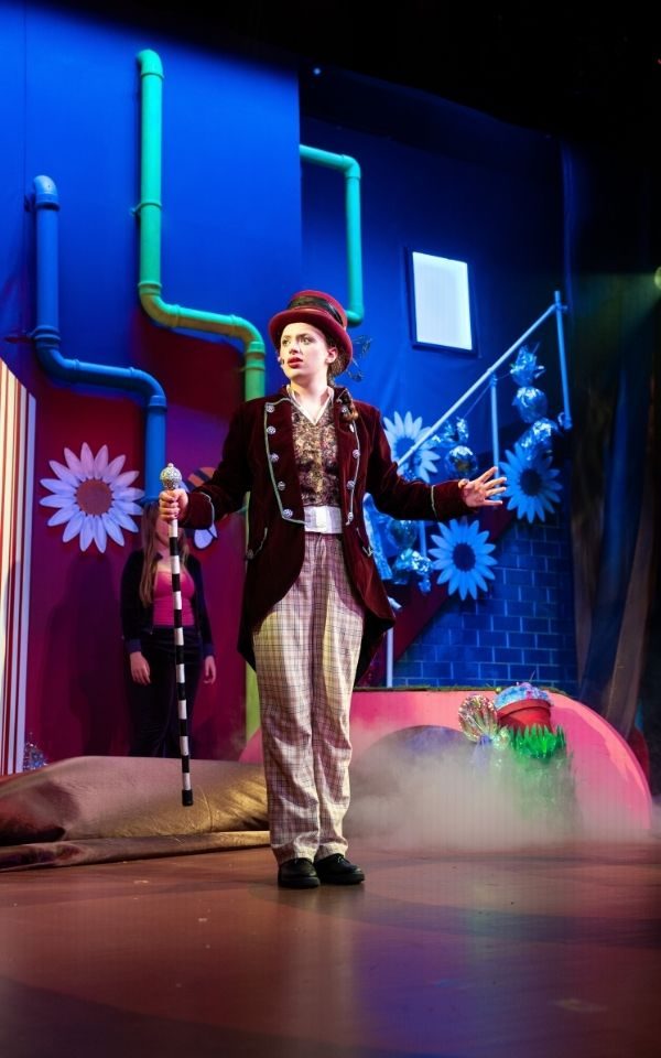 Wonka's factory. Credit Chris Coote Wonka stands in the centre of the shot with his cane, top hat and finery, as the colourful cogs of the factory are visible in the background