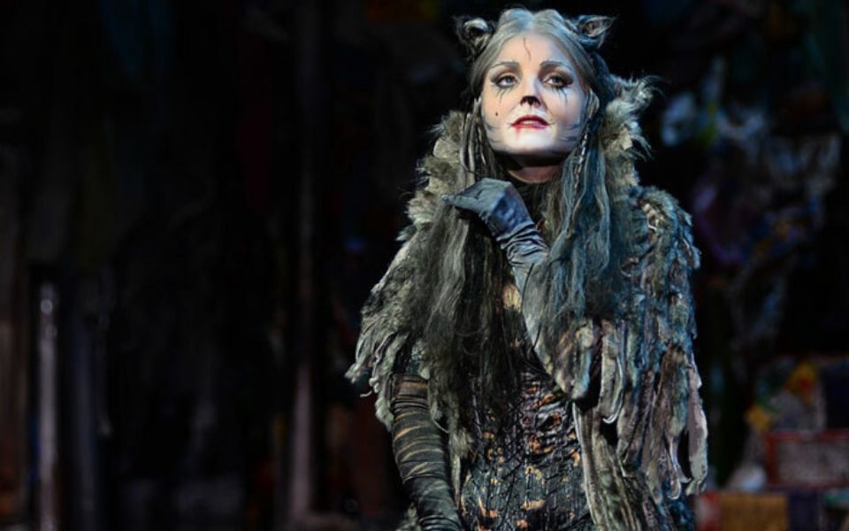 Kerry Ellis dressed as Grizabella in Cats. She has her face painted like a cat and a wig to look like cat ears dark with a dark-coloured shabby costume with gloves.