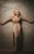 Kerry Ellis Kerry Ellis wearing a nude dress with bead embellishments and beading making up a long, fringed skirt. She leans against a beige wall with her arms outstretched while smiling and closing her eyes.