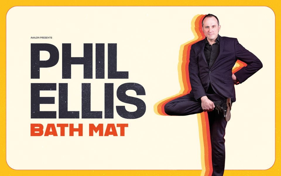 Phil Ellis stands upright, one hand on hip and his leg raised to his hip. He wears a dark suit and is surrounded by a silhouette of yellow, orange and red. Text reads: Avalon presents Phil Ellis Bath Mat