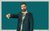 Pierre Novellie In a forest green suit and shirt patterned with palm trees, a straight-faced Pierre Novellie looks off-camera and points his finger downwards, set against a plain blue-green backdrop.