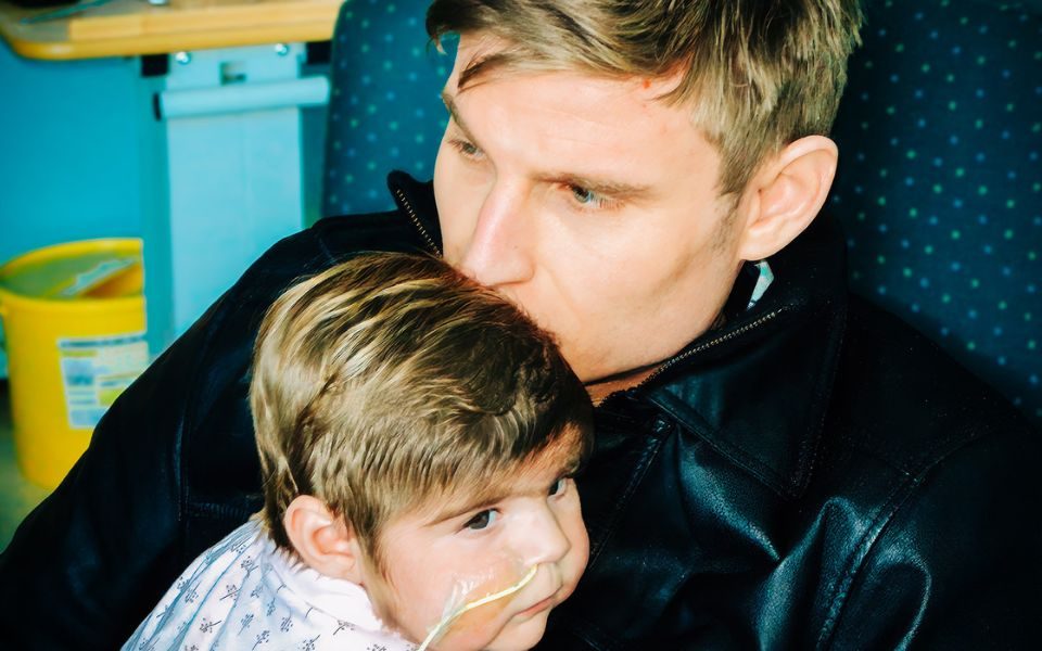 Digital photo of Scott Bennett comforting and holding a baby with an oxygen tube in his arms.