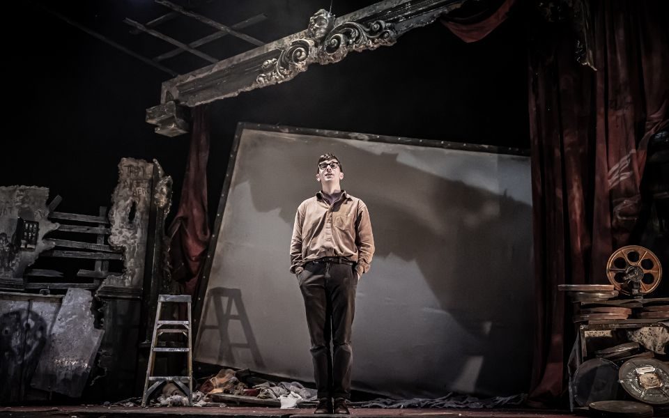 Herbert stood alone on stage, surrounded by elements of a dilapidated cinema