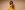 Sindhu Vee Sindhu Vee spins around a flowing yellow dress and looks behind her shoulder with a smile in front on a pale brown backdrop. She has a blowout hairdo and gold earrings and bangle.
