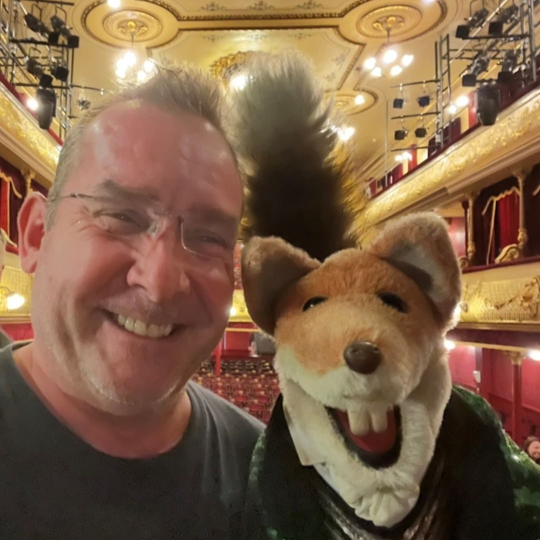 A selfie of Garry Barnes and Basil Brush, the puppet fox, smiling with the City Varieties auditorium behind them.