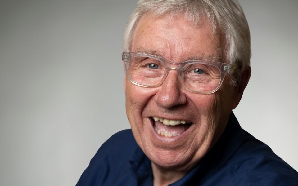 Gregor Fisher smiles at the camera in front of a plain grey background.