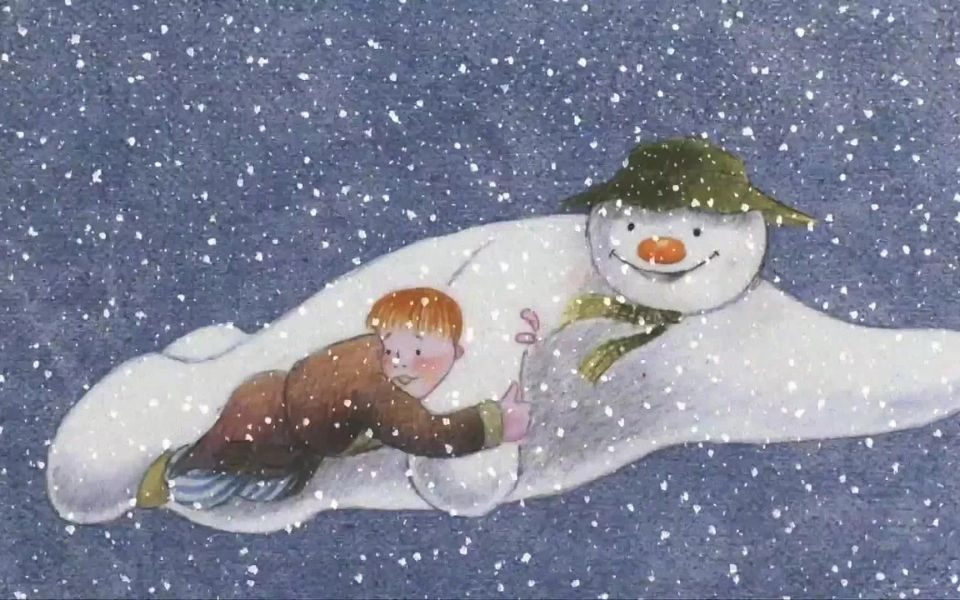 Illustrated animated image. A red-haired child in a dressing gown and striped pyjamas holds onto the arm of a large, smiling Snowman gliding through the snowy sky.