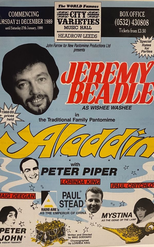 A poster for Aladdin, 1999, showing a collage of cast headshots and illustrations of a magic lamp and a treasure chest. Notably, Jeremy Beadle is featured as top billing.