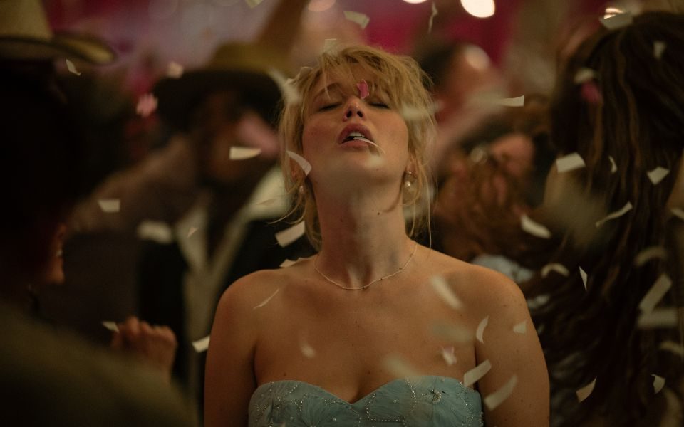 Jennifer Lawrence has her eyes closed and head tilted back as she stands in the middle of a busy dancefloor, confetti landing on her.