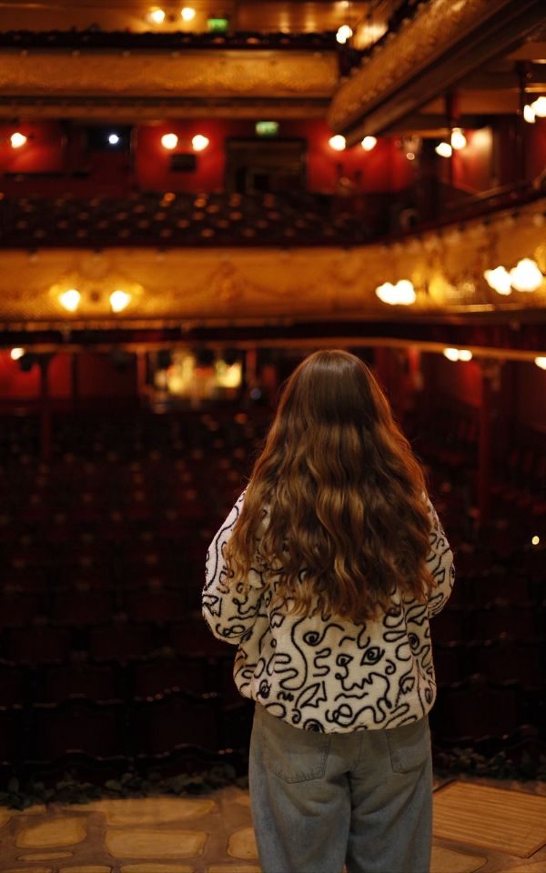 Joni Franieczek standing with her back to the camera looking out at the City Varieties auditorium.
