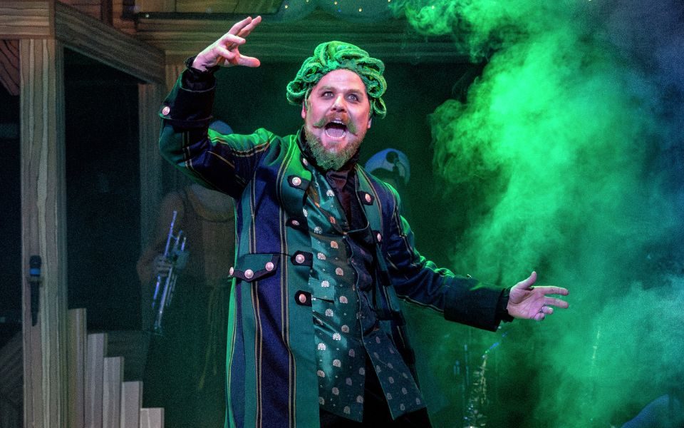 Kenny Davies as panto villain Fleshcreep looking sinister wearing a long green and black coat with a long satin green patterned waistcoat underneath.