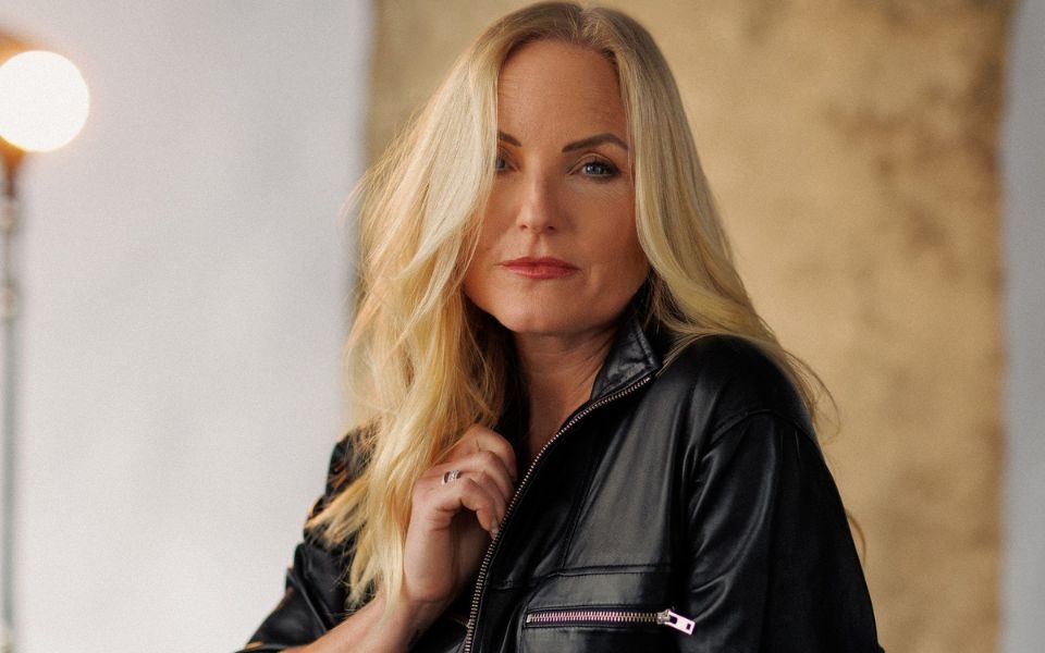 Kerry Ellis casually holds the collar of her black leather bomber jacket.