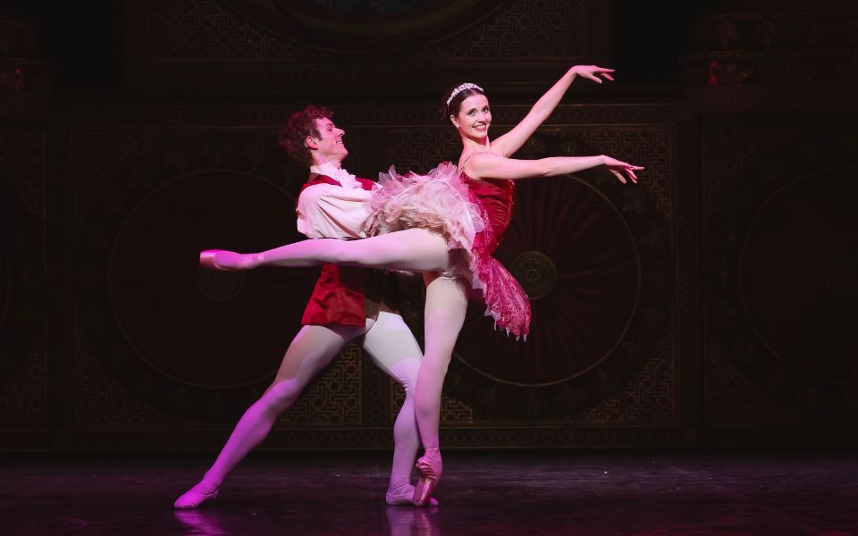 Dominique Larose in a dark pink tutu as the Sugar Plum Fairy being held in a ballet pose by Jonathan Hanks.