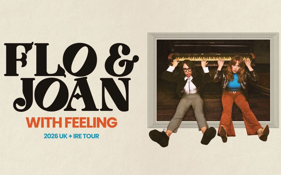 Inside a picture frame, Flo and Joan sit on the floor with their legs extended, and their arms playing a piano positioned behind their heads. Bold text reads: Flo & Joan: With Feeling. 2026 UK + IRE tour.
