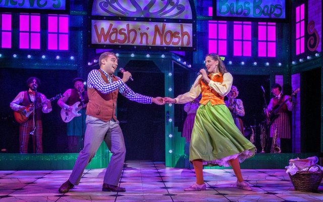 Harry F Brown as Aladdin and Laura Andresen Guimaraes as Princess Peachblossom sing together and hold hands onstage in Aladdin The Rock n Roll Panto.