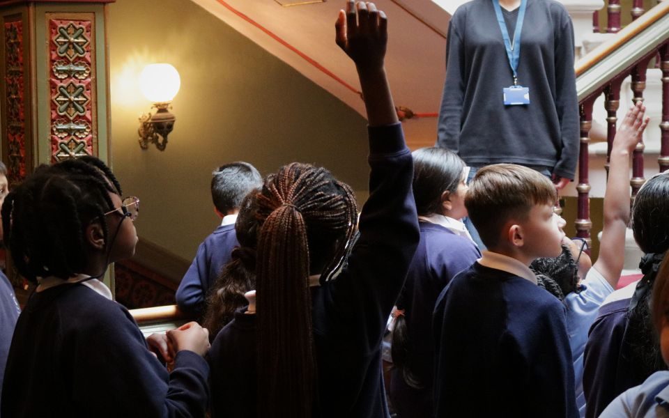 A group of students listen to a talk in The Grand Theatre auditorium, as one raises their hand.