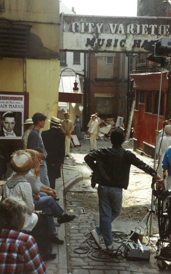 A film crew and actors in period costume stand on a cobbled street outside The City Varieties Music Hall, the sign prominent in the top half of the photo.