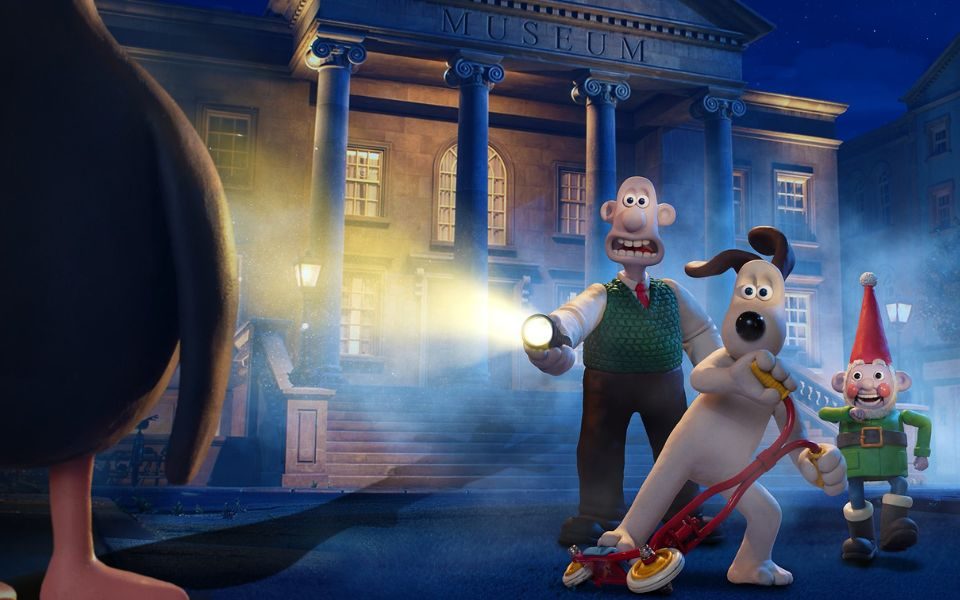 Wallace and Gromit, on a red scooter, stand outside a grand museum on a misty evening, accompanied by a colourful garden gnome. Wallace shines a torch on a silhouetted figure in the corner of the frame.