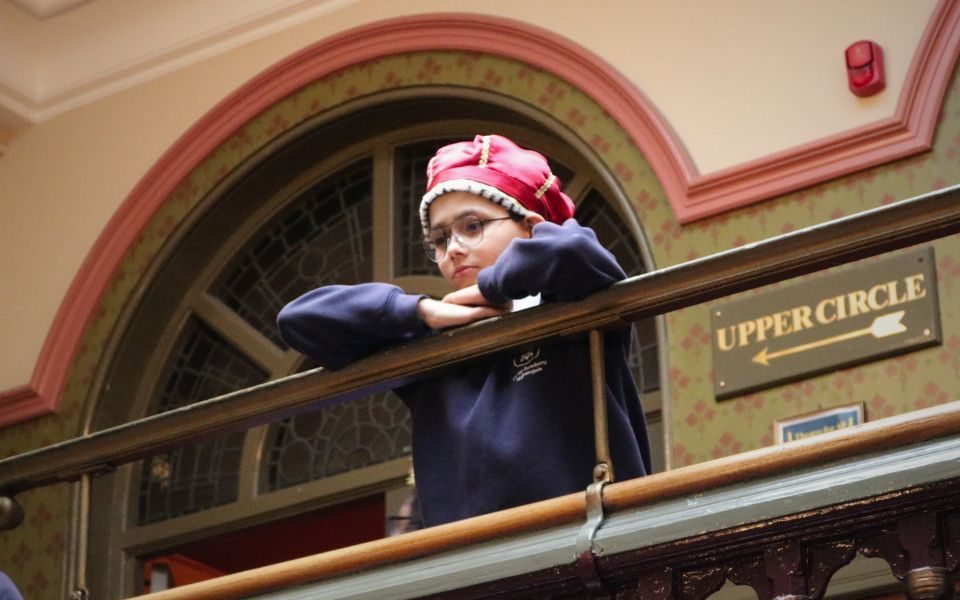 A student stands by the Upper Circle, dressed in a royal costume with a crown.