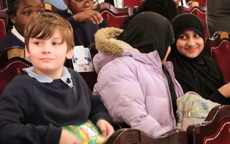 School students sat talking excitedly in a theatre auditorium.