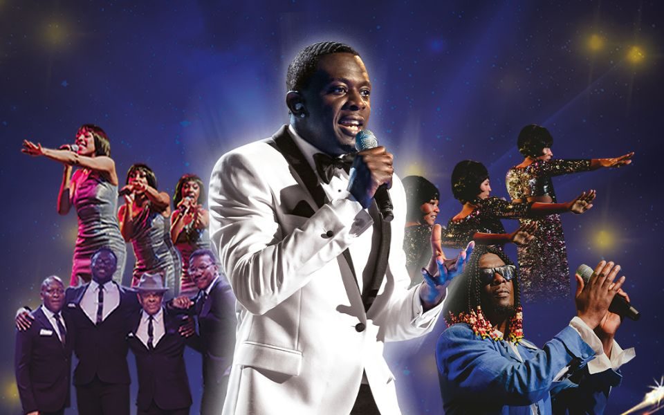 Image of various Motown musicians performing with Bizzi Dixon singing into a microphone in a white suit, front and centre.