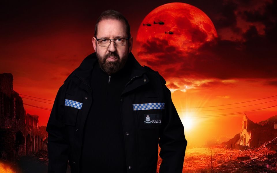 A stern Alfie Moore in police uniform stands in front of a red-tinted apocalyptic landscape, featuring flaming rubble, ruined buildings and helicopter silhouettes in the sky.