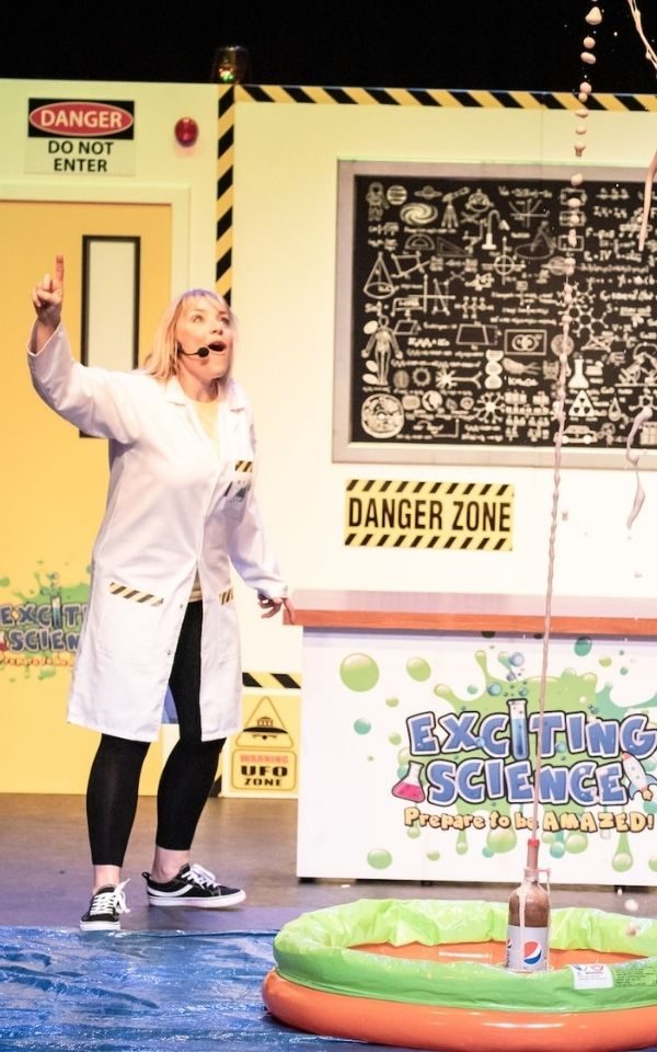 With an expression of excitement, a member of the Exciting Science points as a bottle of Pepsi casts a fountain of liquid high up into the air.