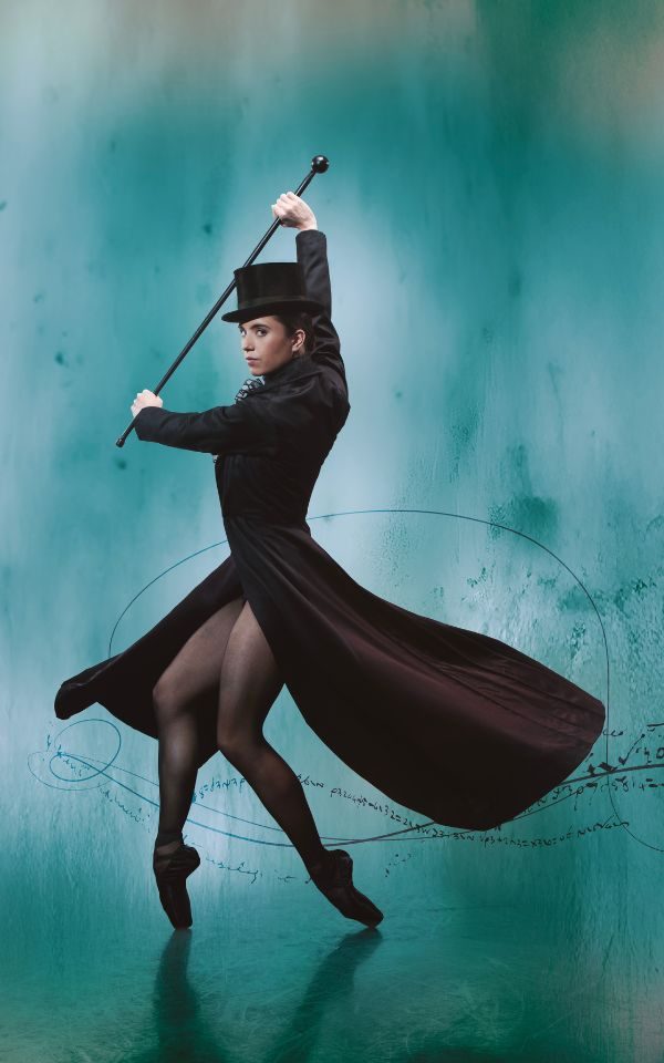 A ballerina in black hat holds a cane against a watercolour background.