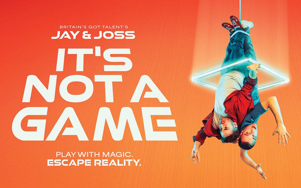Two people dangle upside-down from a rope around their ankles, encased in a bright neon light against an orange background. Text reads: Britain's Got Talent's Jay & Joss. It's Not a Game. Play with magic. Escape reality.