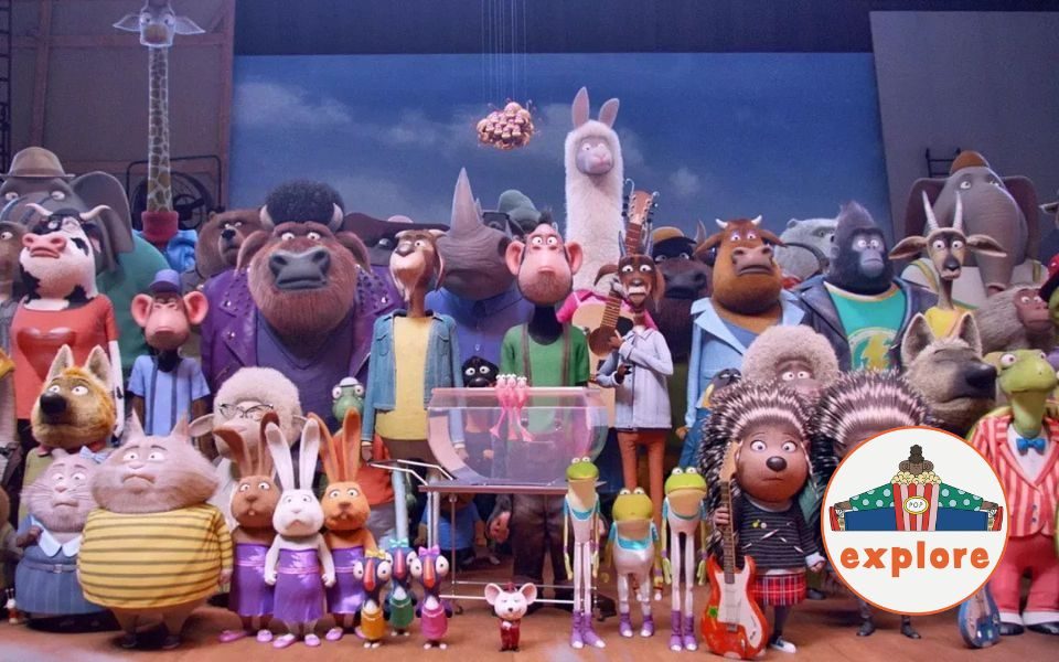Animated still. An eclectic crowd of anthropomorphic animals stood up straight, all looking perplexed. The porcupines at the front of the crowd are holding guitars. In the bottom right corner, a roundel featuring a playful illustration of a person sat peering over a bucket of popcorn, on the word 'explore'.