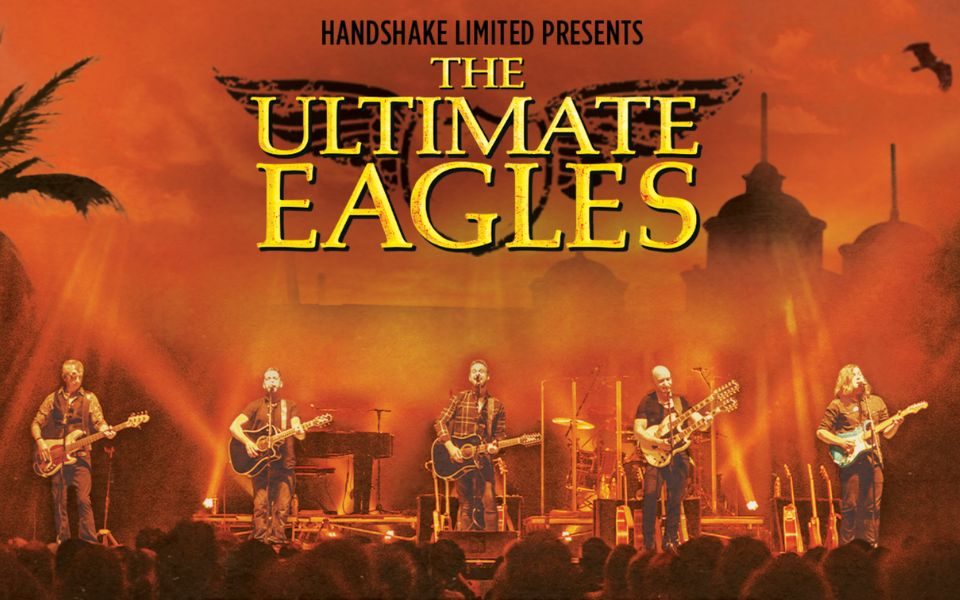 In front of a hazy, deep orange skyline of buildings, palm trees and a soaring eagle, six guitarists perform on stage to a crowd. Text reads: Handshake Limited presents The Ultimate Eagles.