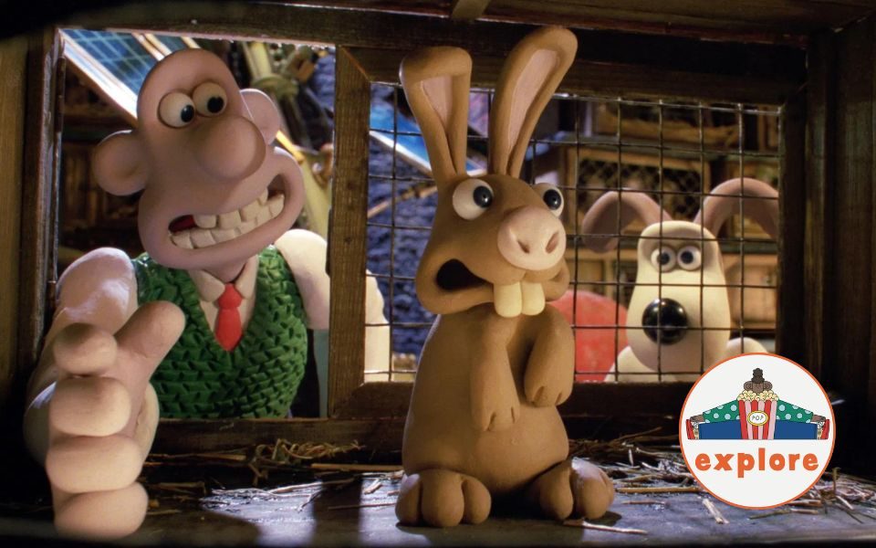 Stop-motion animated still. Gromit watches on as Wallace reaches into a rabbit hutch, where a rabbit stands scared. In the bottom right corner, a roundel featuring a playful illustration of a person juggling stood on the word 'explore'.