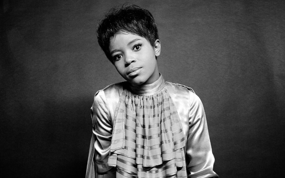 Black and white headshot of PP Arnold, tilting her head to the side with a neutral expression and cropped hair, in front of a grey backdrop.