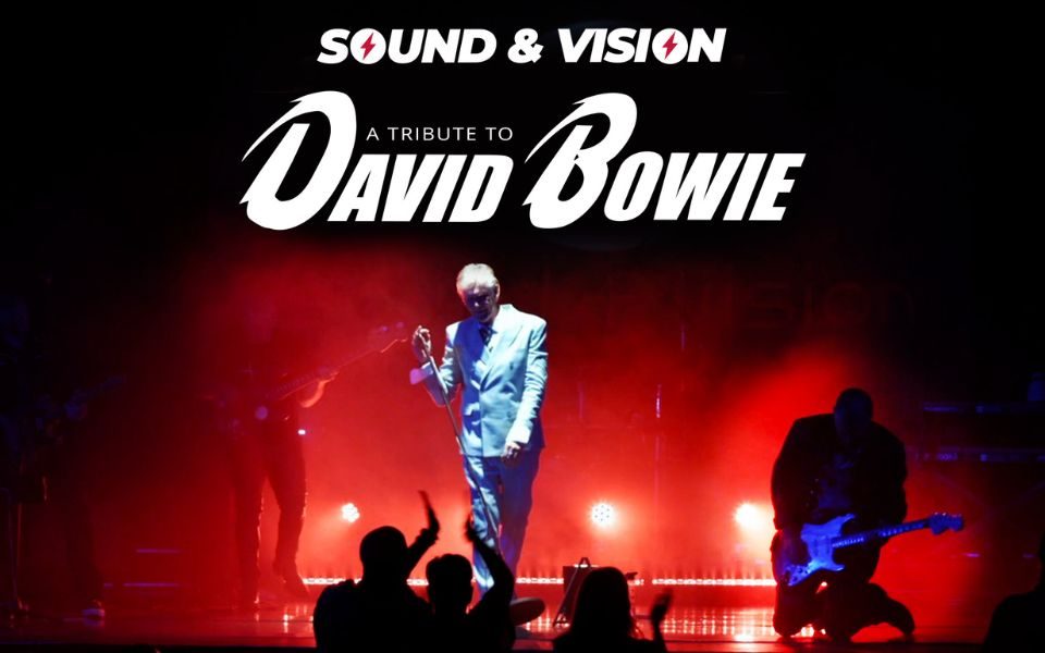 On a hazy stage with red spotlights, a David Bowie tribute act performs in a white suit, accompanied by two guitarists. Text reads: Sound and Vision. A tribute to David Bowie.