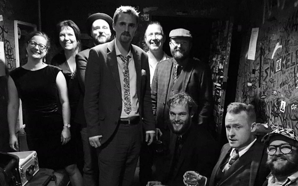 A black and white photo of The Frank Burkitt Band and collaborators posing together