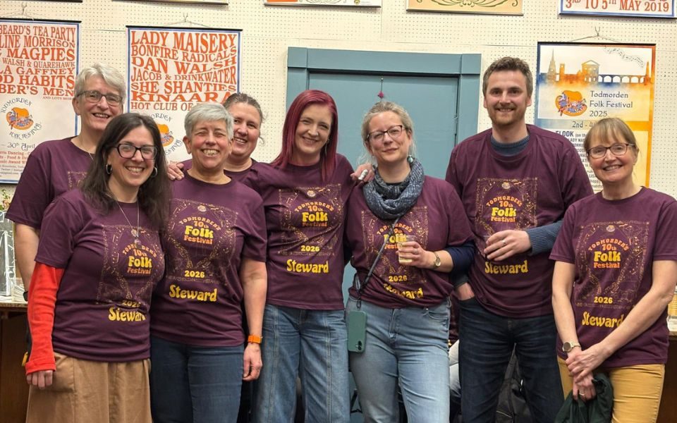 Frank smiling with a group of people wearing Todmorden Folk Festival 2026 shirts